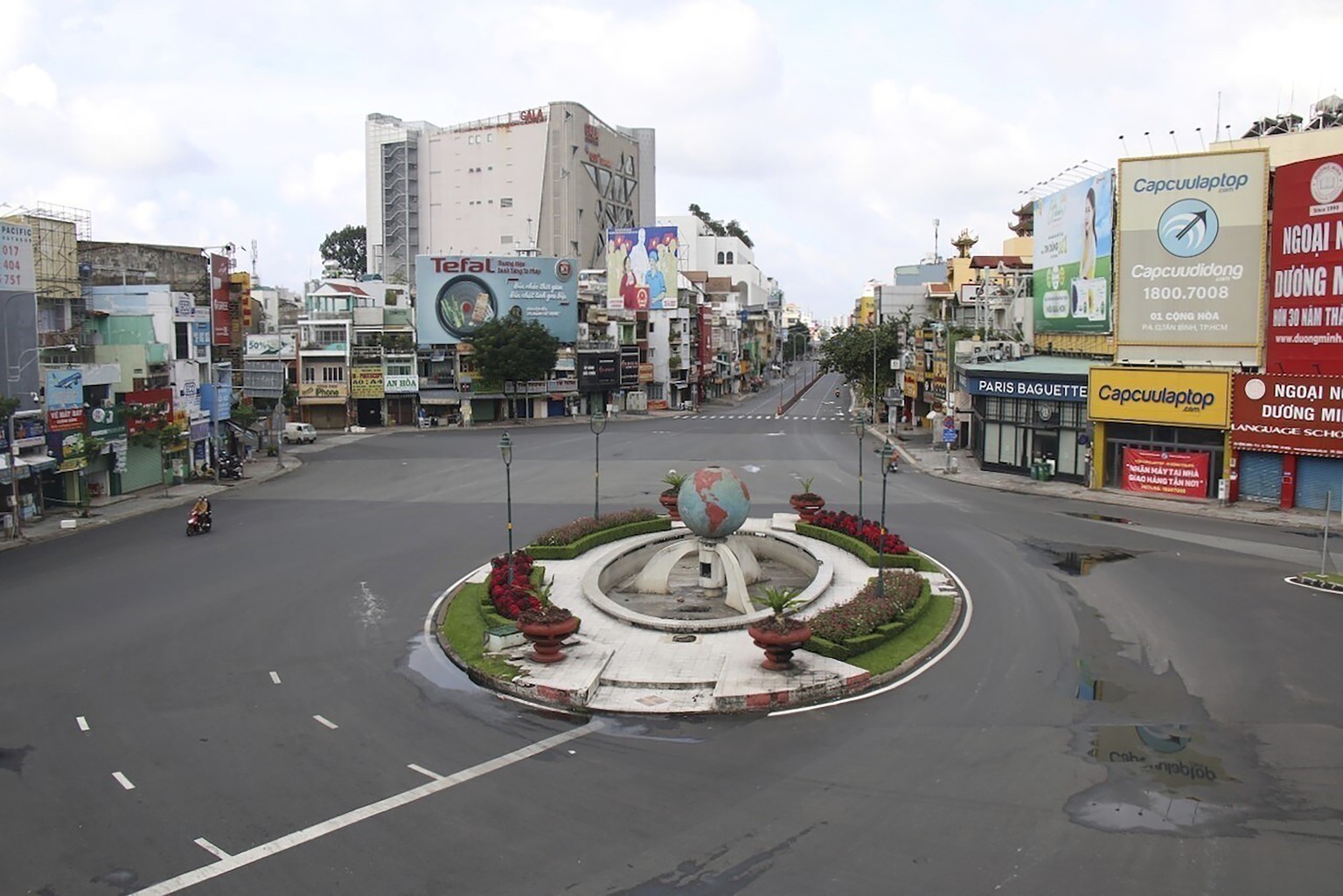 People ride on a motorcycle through a quiet intersection in Ho Chi Minh City, Vietnam, Monday, Aug. 23, 2021. Vietnam&#039;s largest metropolis Ho Chi Minh City has ordered a strict lockdown to help c ...