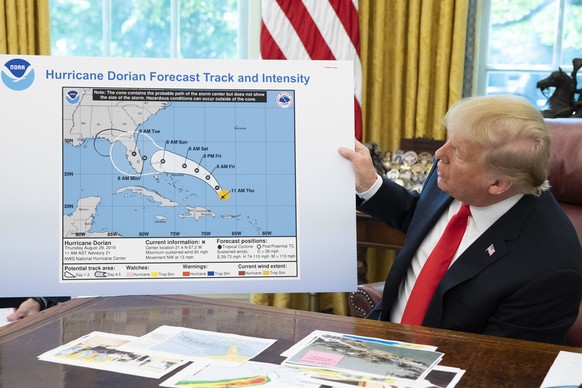 epa07817429 US President Donald J. Trump holds up a National Oceanic and Atmospheric Administration map of a previously projected path of Hurricane Dorian, while participating in a briefing on Hurrica ...