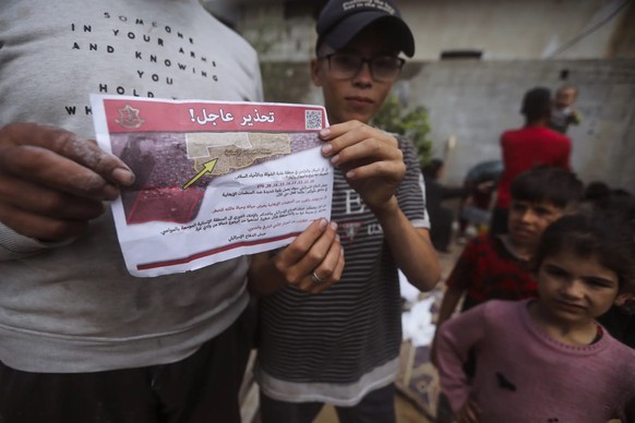 Palästinenser im südlichen Gaza-Streifen halten den israelischen Evakuierungsbefehl in arabischer Sprache vom 6. Mai in die Kamera.