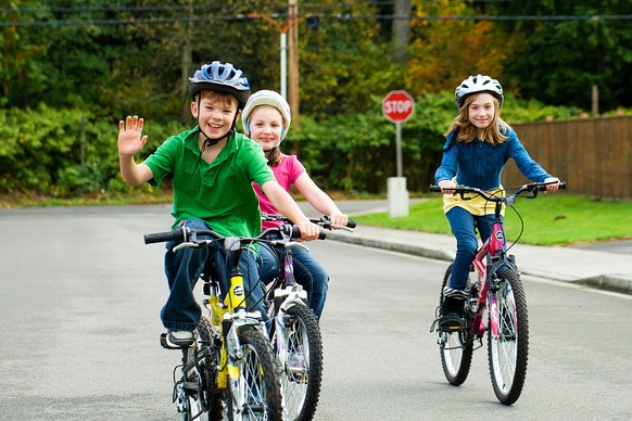 Velofahrende Kinder mit Helm in einer Seitenstrasse