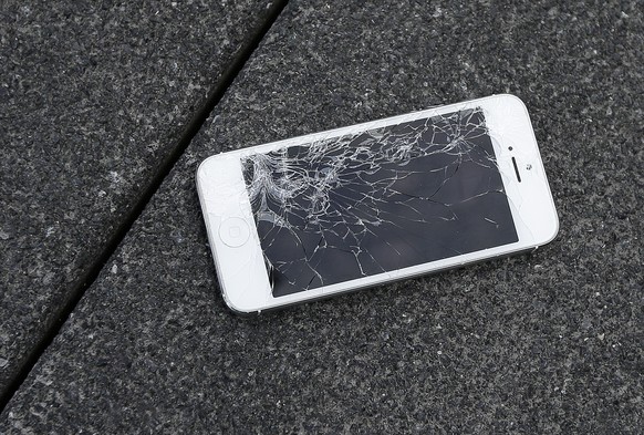 This Aug. 26, 2015 photo shows an Apple iPhone with a cracked screen after a drop test from the DropBot, a robot used to measure the sustainability of a phone to dropping, at the offices of SquareTrad ...