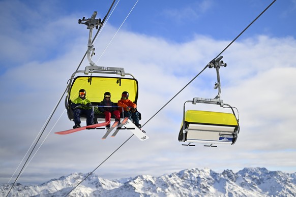 Skifahrer nehmen einen Sessellift, aufgenommen bei der Eroeffnung der Skisaison, am Samstag, 19. November 2022, auf Parsenn in Davos. (KEYSTONE/Gian Ehrenzeller)