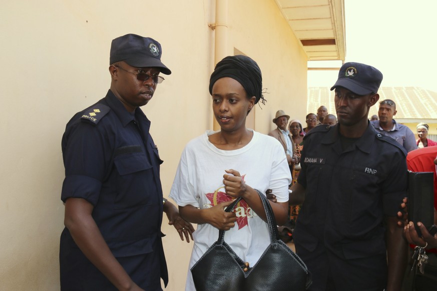 FILE - In this Friday, Oct. 6, 2017 file photo, former Rwanda presidential candidate Diane Rwigara is escorted by policemen to a court where she denied charges of insurrection and forgery that she say ...