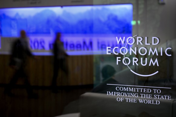 The WEF logo depicted on a window of the convention center as participants are reflected in the convention center on the eve of the 54th annual meeting of the World Economic Forum, WEF, in Davos,…