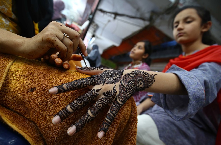 epa09922374 Girls get their hands ornamented with Henna for the upcoming Eid al-Fitr festival, the celebrations marking the end of the holy fasting month of Ramadan, in Karachi, Pakistan, 02 May 2022. ...