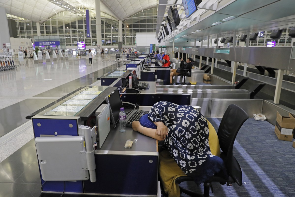 Stranded travelers sleep at the check-in counters at the Hong Kong International Airport, Monday, Aug. 12, 2019. One of the world's busiest airports canceled all flights after thousands of Hong K ...