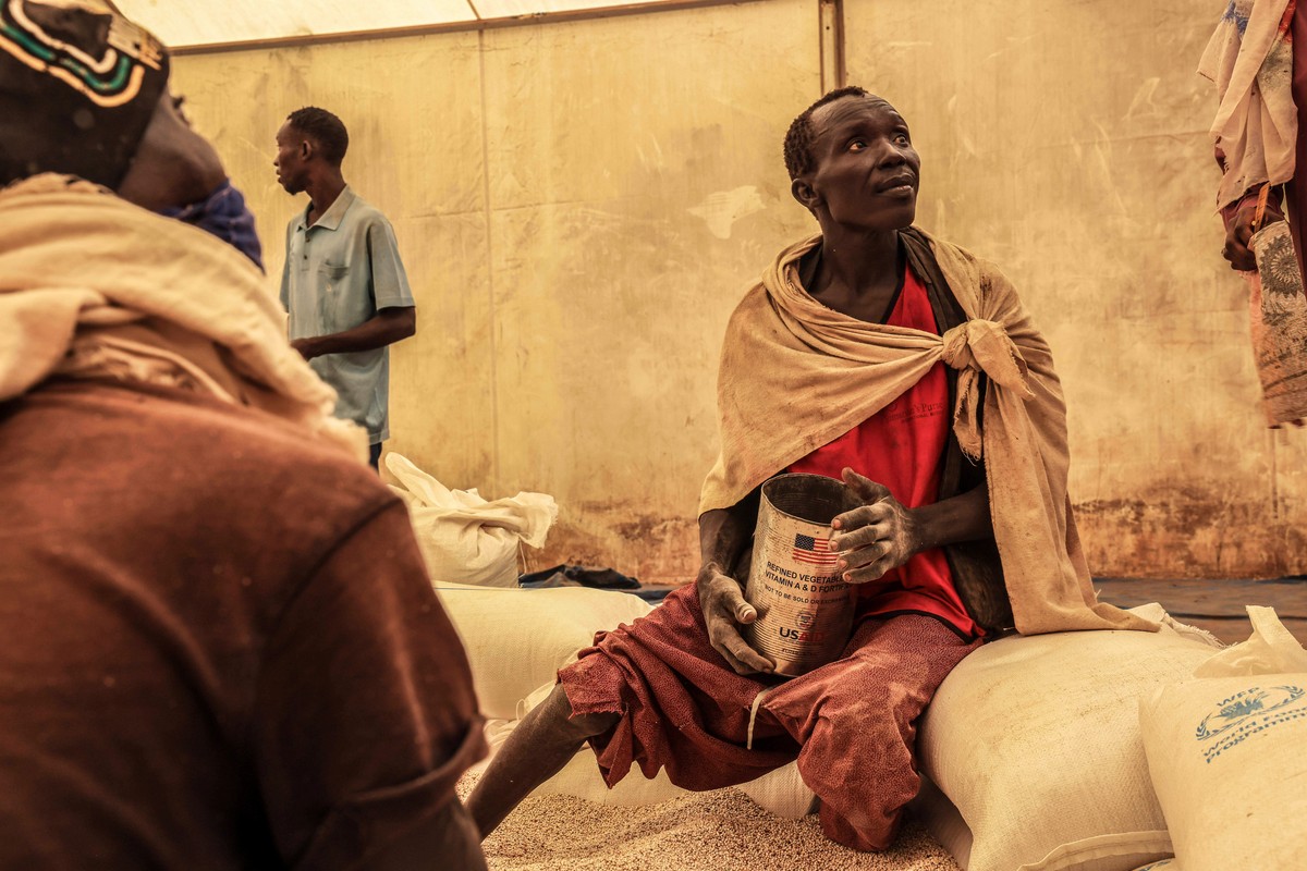 FILE - A man scoops up portions of wheat to be allocated to each waiting family after distribution by the U.N. World Food Programme (WFP) in the Gendrassa Refugee Camp, Maban, South Sudan, Wednesday,  ...