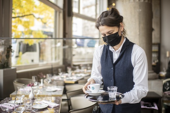 Eine Frau mit Atemschutzmaske serviert einen Espresso im Restaurant Terrasse, aufgenommen am Dienstag, 27. Oktober 2020 in Zuerich. (KEYSTONE/Ennio Leanza)