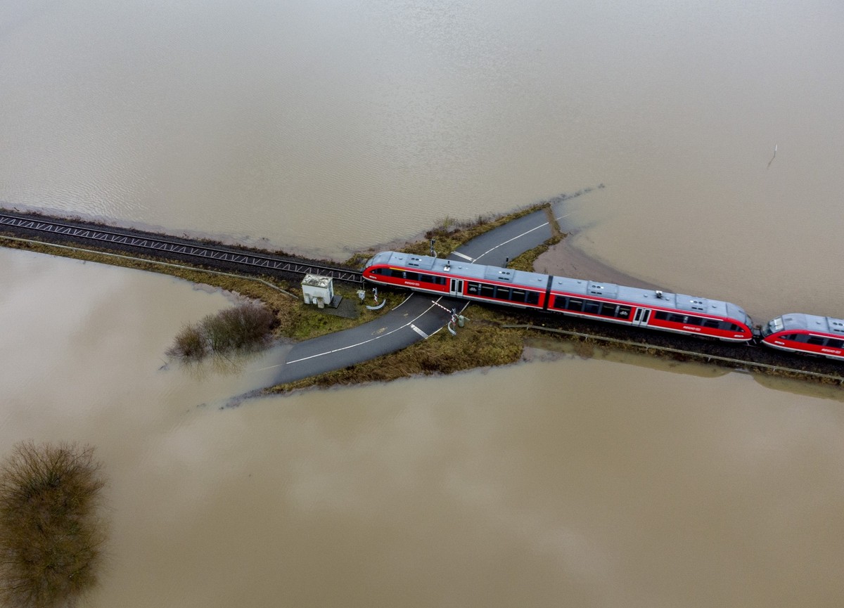 A train passes a rail road crossing that is surrounded by flooding caused by rain and melting snow in Nidderau near Frankfurt, Germany, Wednesday, Feb. 3, 2021. (KEYSTONE/AP Photo/Michael Probst)