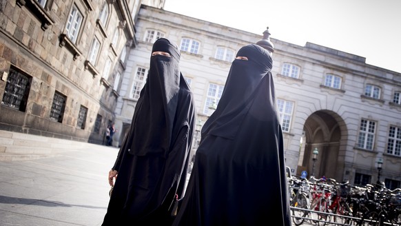 epa06775145 Women wearing the niqab walk in front of the Danish Parliament at Christiansborg Castle in Copenhagen, Denmark, 31 May 2018. A majority in the Danish Parliament adopted a ban wearing niqab ...