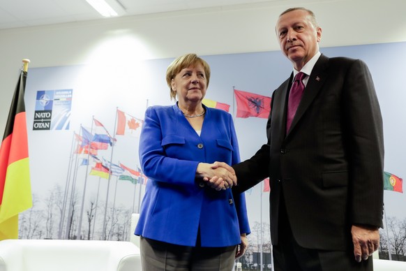 German Chancellor Angela Merkel, left, and Turkish President Recep Tayyip Erdogan, right, shake hands prior to a bilateral meeting on the sideline of a summit of heads of state and government at NATO  ...