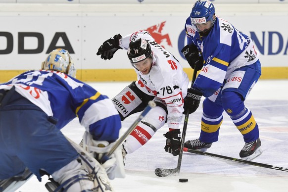 Davos&#039; Gilles Senn, left, and Daniel Rahimi, right, fight for the puck with Team Canada&#039;s Marc-Antoine Pouliot, center, during the game between HC Davos and Team Canada, at the 90th Spengler ...