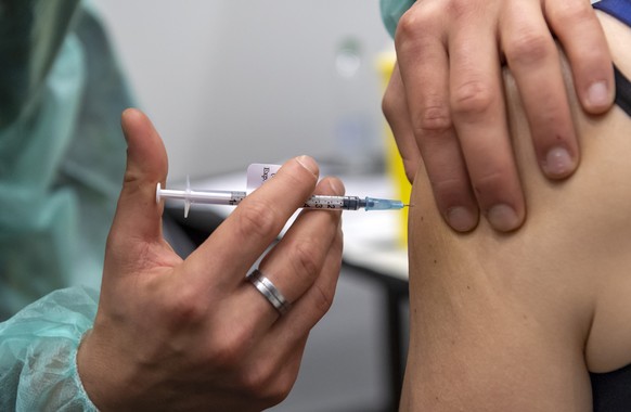 Ein Durchdienersoldat der Sanitaetsschule Airolo verabreicht eine Booster-Impfung mit dem Covid-19-Impfstoff im Impfzentrum in Delemont, am Dienstag, 14. Dezember 2021. (KEYSTONE/Georgios Kefalas)