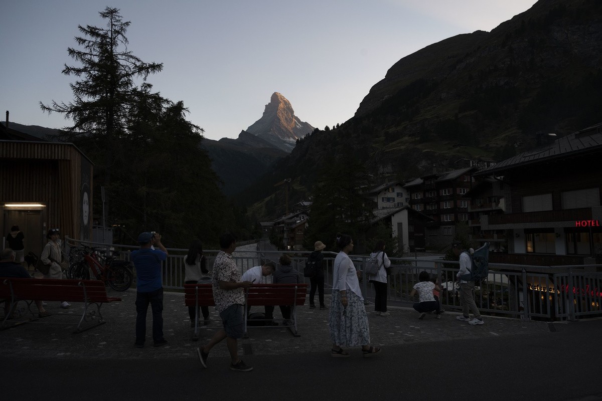Touristen versammelt auf einer Bruecke ueber der Mattervispa betrachten das Matterhorn in der Abenddaemmerung, fotografiert am Sonntag, 24. Juli 2022 in Zermatt. (KEYSTONE/Christian Beutler)