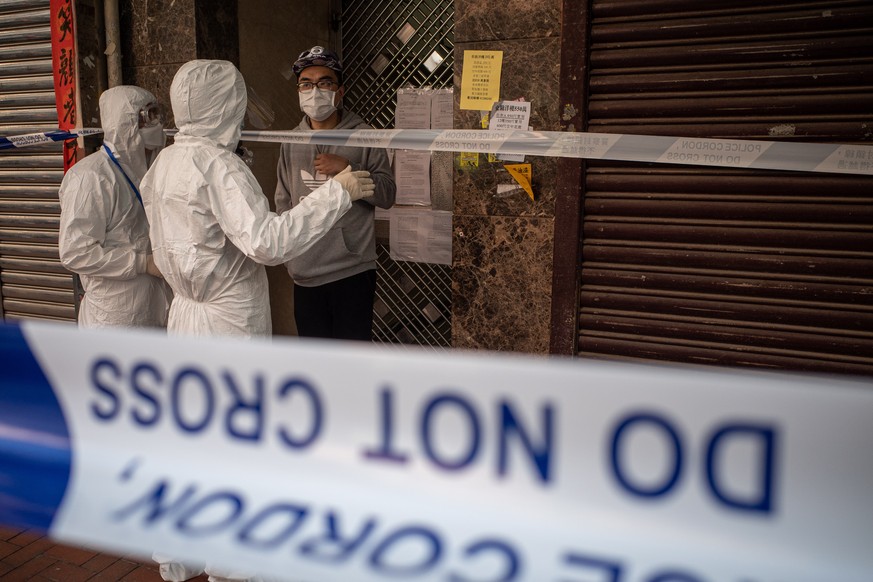 epaselect epa08959113 A local resident is forbidden to leave his building by a civil servant in face mask and protective gown during a lockdown in Jordan, Hong Kong, China, 23 January 2021. The Hong K ...