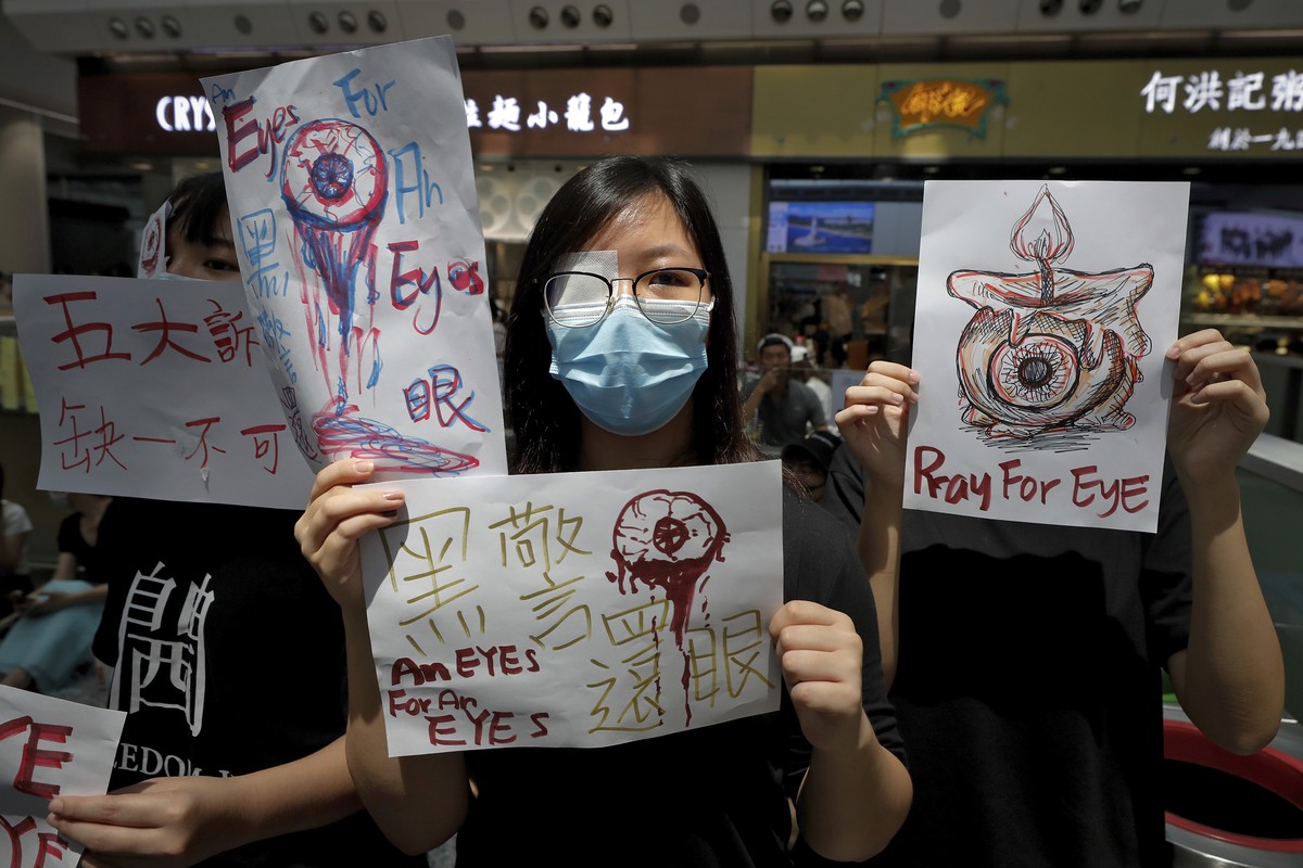 People hold signs which read " Black Police, Return eye," bottom center, during a protest at the arrival hall of the Hong Kong International airport in Hong Kong, Monday, Aug. 12, 2019. It i ...