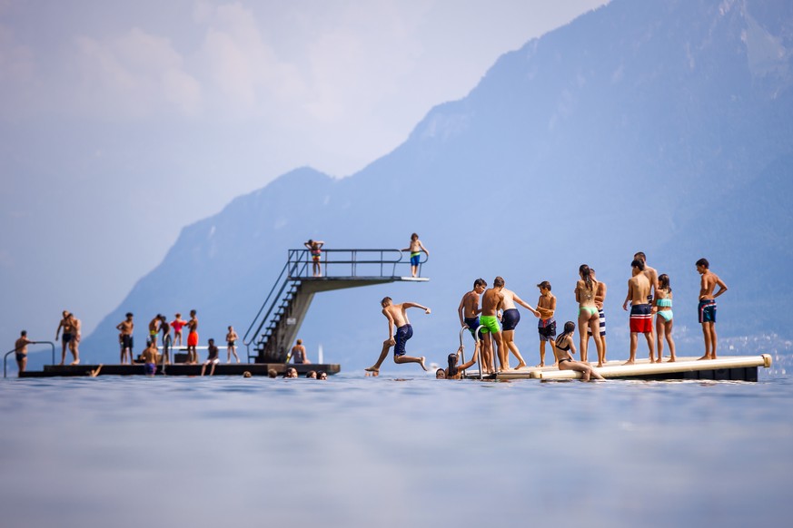People enjoy the sunny and warm summer weather on a diving platform on the shore of Lake Geneva, in Lutry, Switzerland, Wednesday, July 25, 2018. (KEYSTONE/Valentin Flauraud)