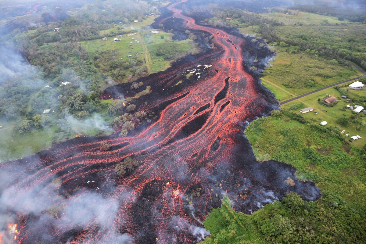 FILE - In this May 19, 2018 aerial file photo released by the U.S. Geological Survey, lava flows from fissures near Pahoa, Hawaii. White plumes of acid and extremely fine shards of glass billowed into ...