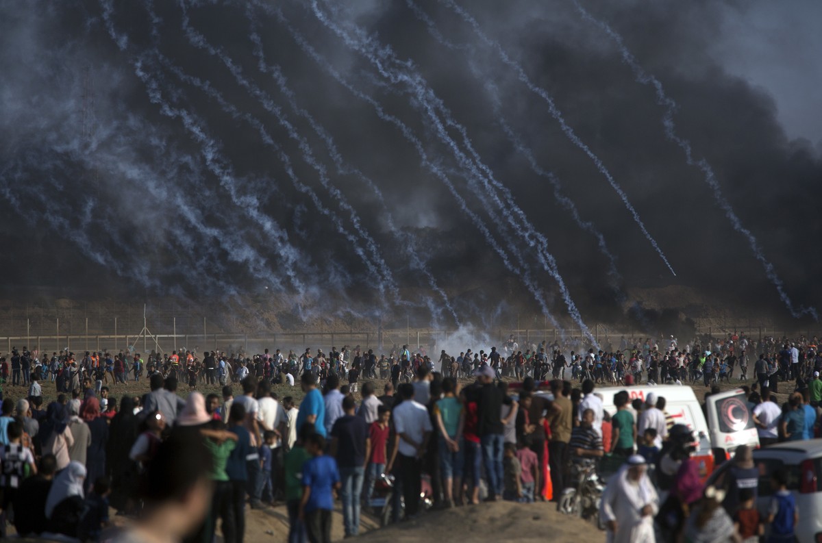 Teargas canisters fired by Israeli troops fall over Palestinians during a protest at the Gaza Strip's border with Israel, Friday, July 13, 2018. Gaza's Health Ministry says a 15-year-old Pal ...