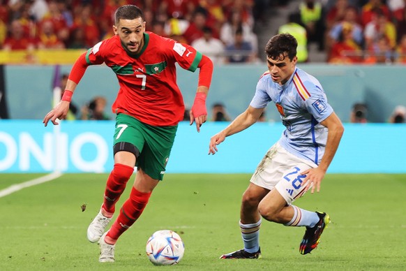 epa10352035 Hakim Ziyech of Morocco in action against Pedri (R) of Spain during the FIFA World Cup 2022 round of 16 soccer match between Morocco and Spain at Education City Stadium in Doha, Qatar, 06  ...