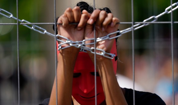 epa06762258 An activist of the association &#039;Together for Africa&#039; wears masks while playing a slave during the staging of a slave market in front of Brandenburg Gate in Berlin, Germany, 25 Ma ...