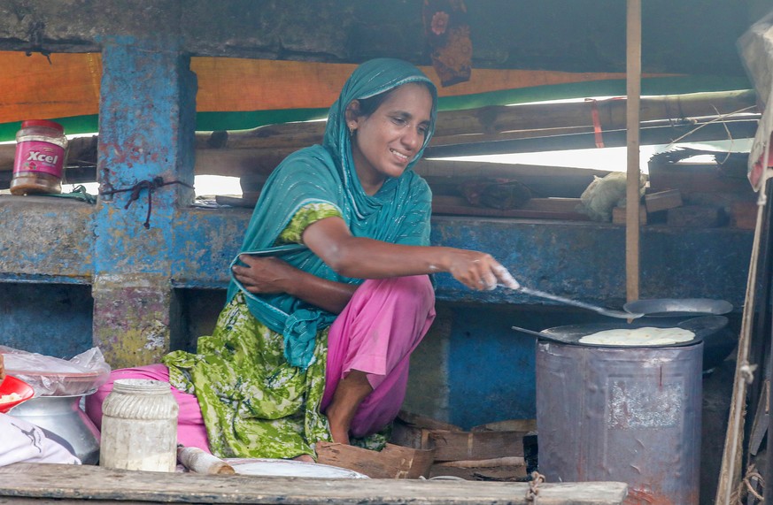 epa13163729 A woman cooks local food near the Buriganga River in Dhaka, Bangladesh, 12 August 2026. Despite severe pollution, the Buriganga River remains a vital lifeline to Dhaka's trade, transp ...
