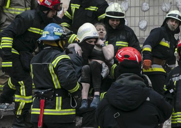 Rescuers carry an injured woman after a Russian missile hit a multi-story building in Dnipro, Ukraine, on Sunday, Jan. 15, 2023. (AP Photo/Yevhenii Zavhorodnii)