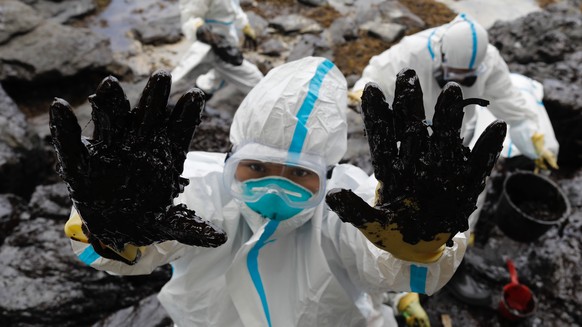 epa10505815 A Philippine fisherman wearing a protective suit shows oily debris on his hands along a beach in the coastal town of Pola, Mindoro Island, Philippines March 6, 2023. Affected fishermen w...