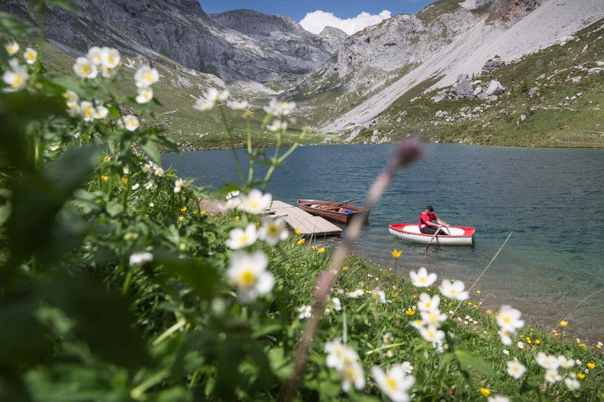 Ein Bergwanderer goennt sich nach einer Tour auf die Sulzfluh im Abstieg eine erfrischende Bootsfahrt aus dem 1870 Meter hoch gelegenen Partnunsee oberhalb St. Antoenien-Partnun im Praettigau, am Donn ...