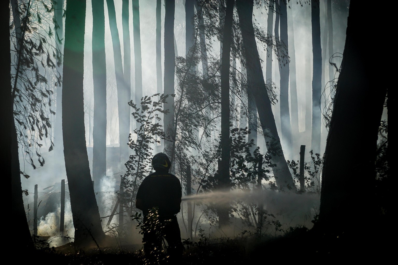 A firefighter hoses down a fire near Naples, southern Italy, Tuesday, July 11, 2017. Firefighters are battling wildfires throughout southern Italy, including along the slopes of the volcano Mount Vesu ...