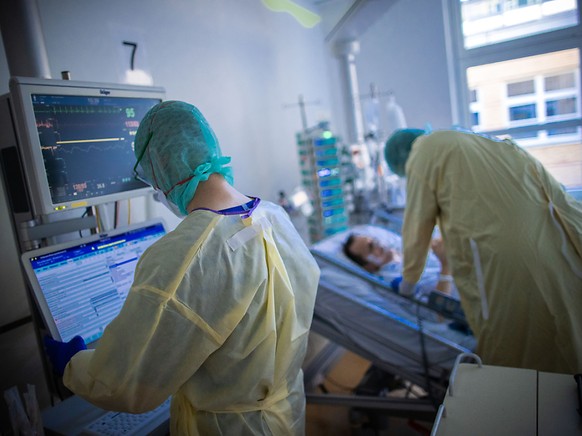 ARCHIV - Pflegekräfte betreuen im besonders geschützten Teil der Intensivstation des Universitätsklinikums einen Covid-Patienten. Erstmals sind in Deutschland mehr als 30 000 neue Infektionen mit dem  ...
