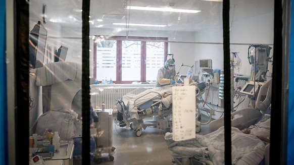 ARCHIV - Ein Intensivpfleger betreut hinter einer Schleuse auf der Intensivstation des Krankenhauses Bethel in Berlin einen Corona-Patienten. Foto: Kay Nietfeld/dpa
