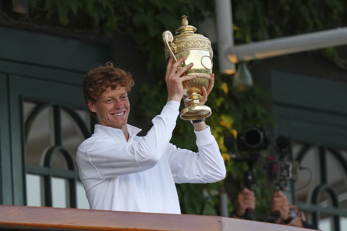 Italy's Jannik Sinner shows the trophy from the balcony of Centre Court after beating Carlos Alcaraz of Spain to win the men's singles final at the Wimbledon Tennis Championships in London,  ...