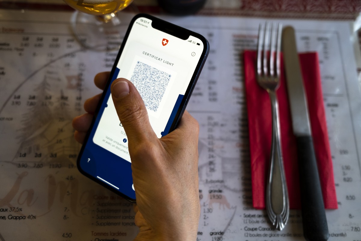 Une personne tient dans sa main un smartphone avec l'application Certifact Covid suisse et un certificat light dans un restaurant ce vendredi 10 septembre 2021 a Rances dans le canton de Vaud. De ...