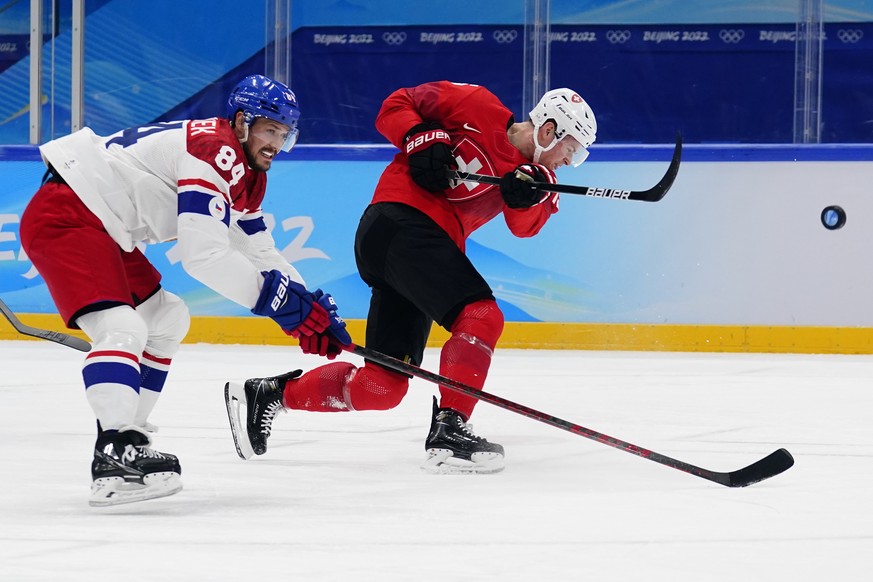 Switzerland&#039;s Gregory Hofmann, right, shoots as he is defended by Czech Republic&#039;s Tomas Kundratek (84) during a men&#039;s qualification round hockey game at the 2022 Winter Olympics, Tuesd ...