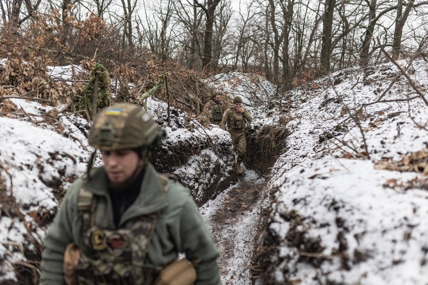 Military mobility of Ukrainian army continues in direction of Bakhmut DONETSK OBLAST, UKRAINE - DECEMBER 6: Ukrainian soldiers walk through a trench towards their FH-70 artillery position, in the dire ...