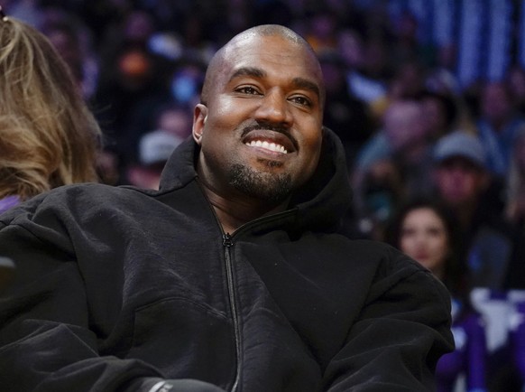 FILE - Kanye West, known as Ye, watches the first half of an NBA basketball game between the Washington Wizards and the Los Angeles Lakers in Los Angeles, March 11, 2022. Adidas saw operating earnings ...
