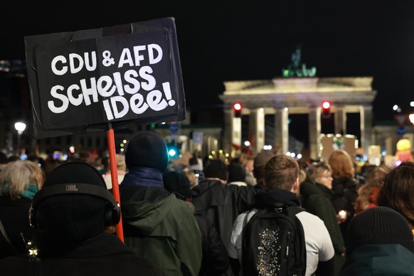 epa11852622 A participant holds a placard that reads &#039;CDU and AFD (parties) shit idea!&#039; during a rally against the far right at the Brandenburg Gate in Berlin, Germany, 25 January 2025. In t ...