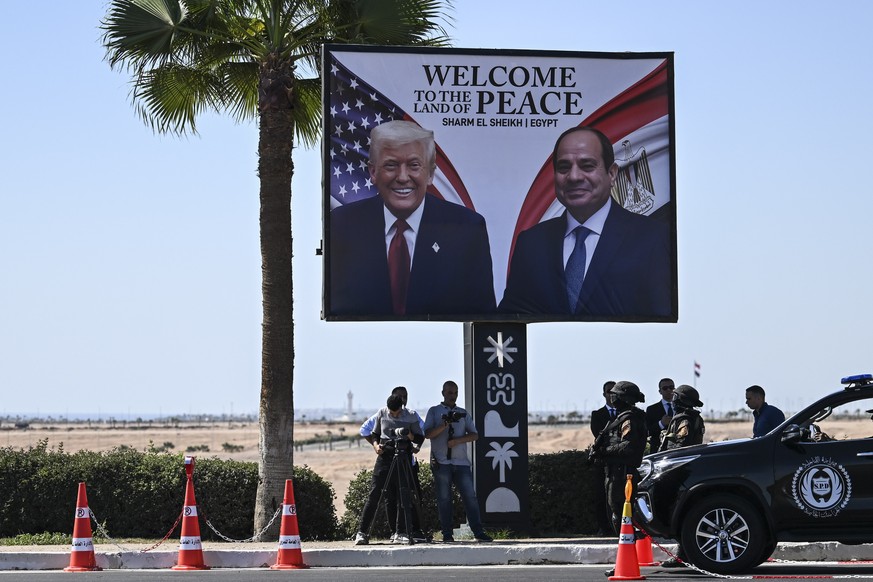 epa12450042 Egyptian security forces and members of the press stand next to a billboard bearing the portraits of US President Donald Trump (L) and Egyptian President Abdel Fattah al-Sisi ahead of the  ...