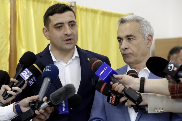 epa12072414 Presidential candidate and far-right party Alliance for the Union of Romanians (AUR) leader George Simion (L) and banned candidate Calin Georgescu speak to media members after casting thei ...