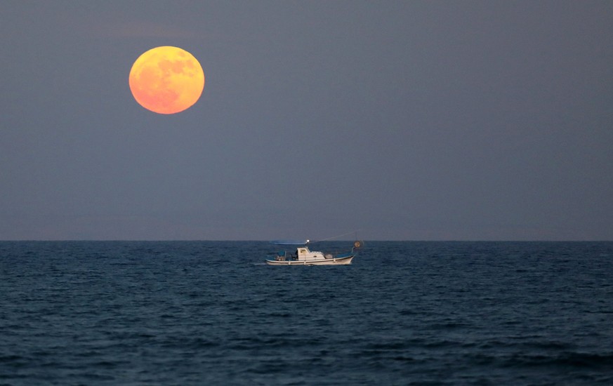 epa06365458 A fishing boat sails as so-called &#039;Supermoon&#039; rises in Larnaca, Cyprus, 03 December 2017. According to the National Aeronautics and Space Administration (NASA) a series of three  ...