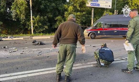 In this handout photo taken from video released by Investigative Committee of Russia on Sunday, Aug. 21, 2022, investigators work on the site of explosion of a car driven by Daria Dugina outside Mosco ...