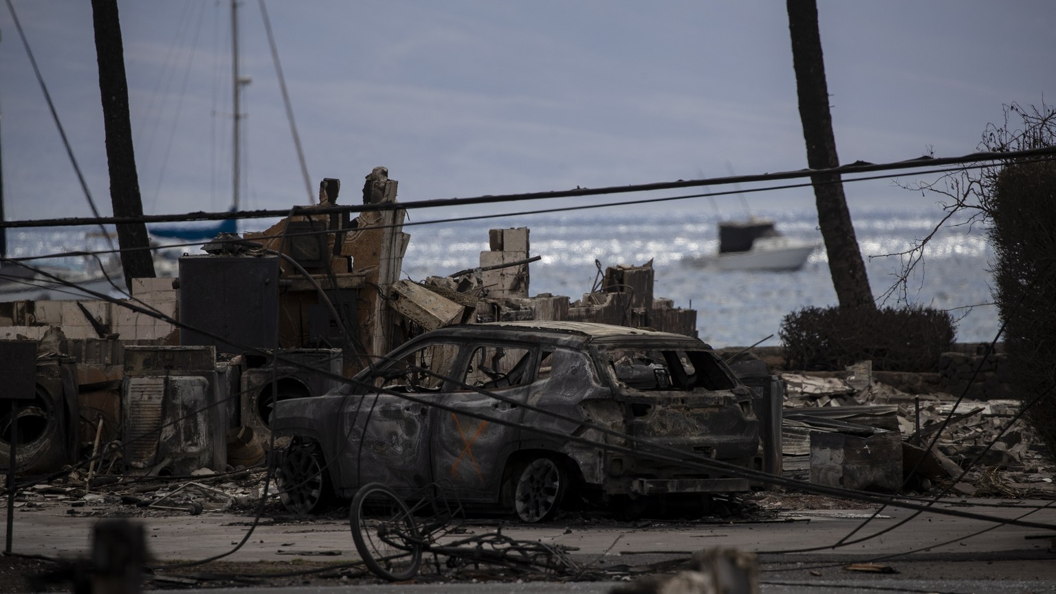 epa10802258 The remians of a burnt car is marked as checked with a spray painted cross after a wildfire swept through a neighborhood in Lahaina, Hawaii, USA, 15 August 2023. At least 99 people were ki ...