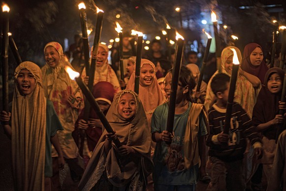 FILE - Muslim girls carry torches during a parade to celebrate the eve of Eid al-Fitr, the holiday marking the end of the holy fasting month of Ramadan, in Polewali Mandar, West Sulawesi, Indonesia, F ...