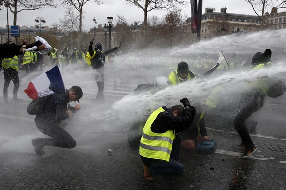 Demonstranten werden in der Nähe des Arc de Triomphe von der Polizei mit Wasser bespritzt.