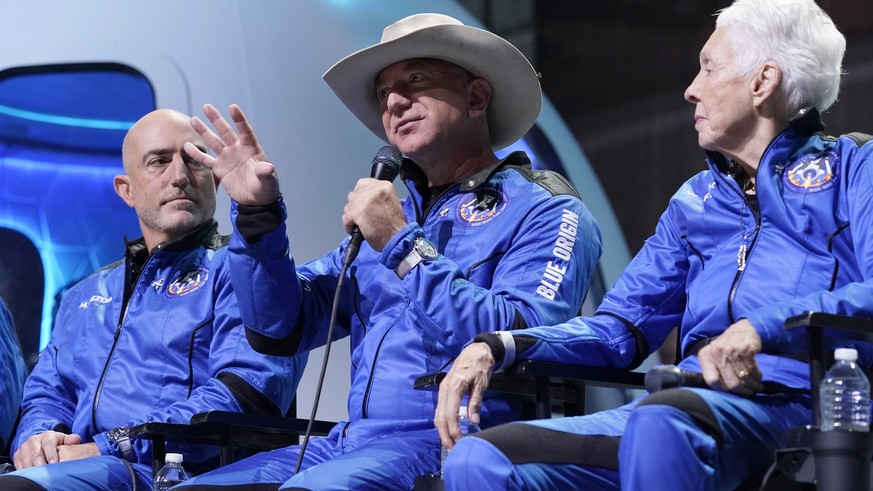 Mark Bezos, left, and Wally Funk, right, listen as Jeff Bezos, center, founder of Amazon and space tourism company Blue Origin makes comments about their flight experience during a post launch briefin ...