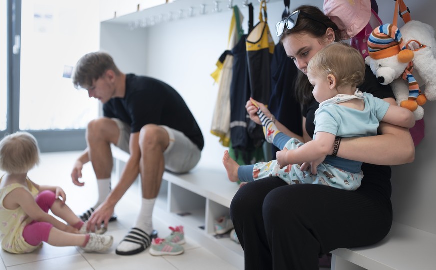 THEMENBILD ZUR LANCIERUNG DER KITA-INITIATIVE --- Betreuungspersonal hilft Kleinkindern beim Anziehen der Schuhe und Sonnenschutzkleidung, bevor es zum Spielen in den Aussenbereich der Kita 6a der Sti ...