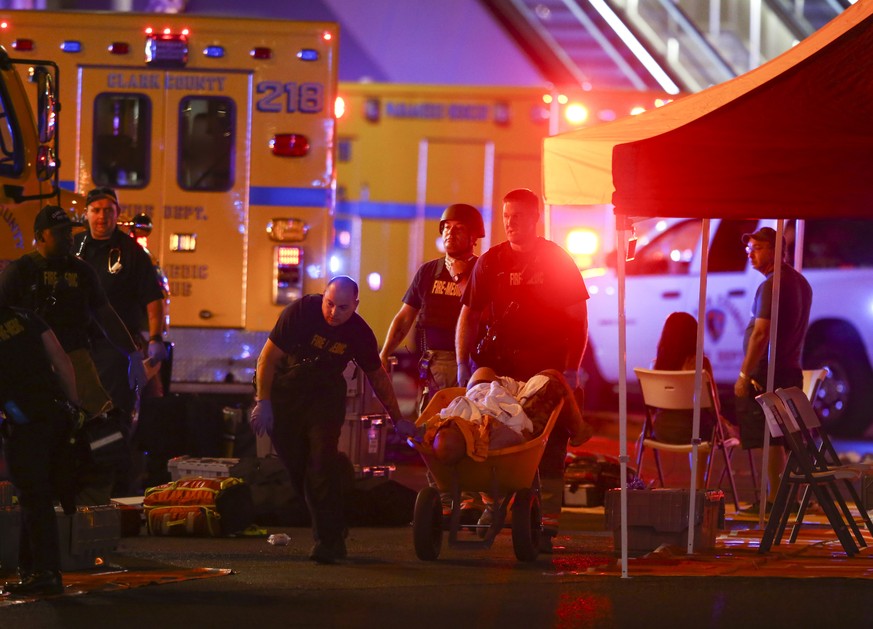 A wounded person is walked in on a wheelbarrow as Las Vegas police respond during an active shooter situation on the Las Vegas Stirp in Las Vegas Sunday, Oct. 1, 2017. Multiple victims were being tran ...