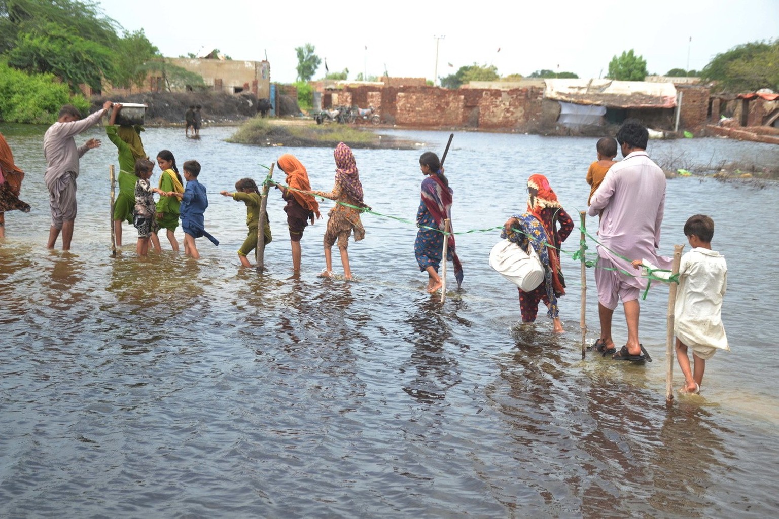 epa10143387 People wade through a flooded area following heavy rains in Sanghar District, Sindh province, Pakistan, 28 August 2022. According to the National Disaster Management Authority (NDMA) on 27 ...