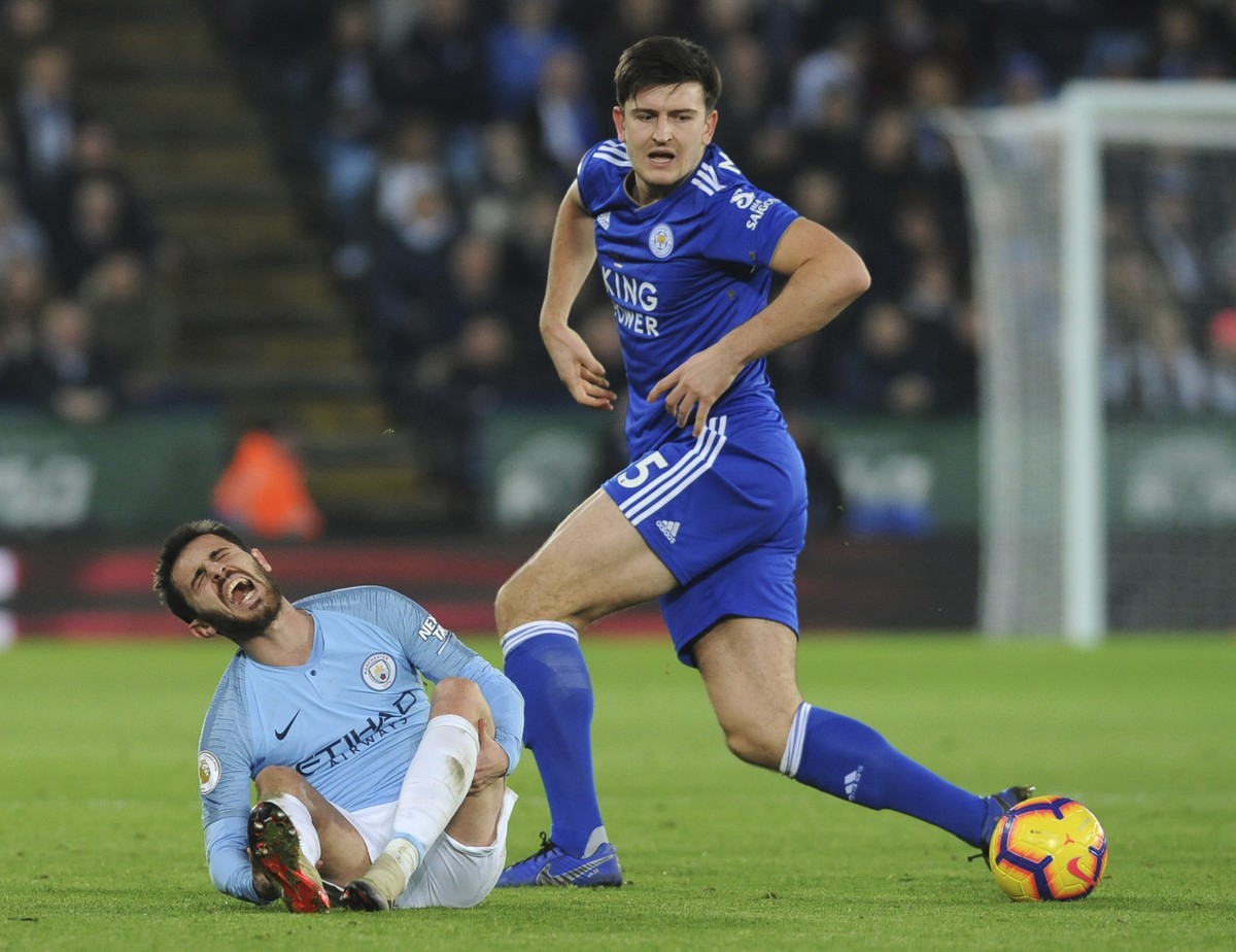 Manchester City's Bernardo Silva, left, lies on the ground after falling as Leicester's Harry Maguire follows the ball during the English Premier League soccer match between Leicester City a ...